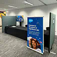 Event partition walls forming a registration desk area with branded signage, display screen, and counter setup inside a conference or exhibition space