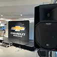 Event stage with microphones, speakers, and branded backdrop display in showroom environment using PA system hire setup