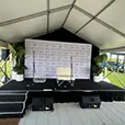 Event stage setup with PA speakers, microphones, branded media backdrop, and presentation area for a live corporate event