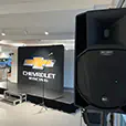 Event stage setup with large speaker on stand, microphones and branded backdrop for a corporate presentation in an indoor venue