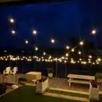 A deck with string lights and a view of the water illuminated by festoon light hire.