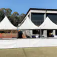 A group of people standing in front of a white tent available for Fete Stall/Tent Hire.