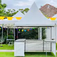 A white tent, part of a fete stall, set up in a grassy area.