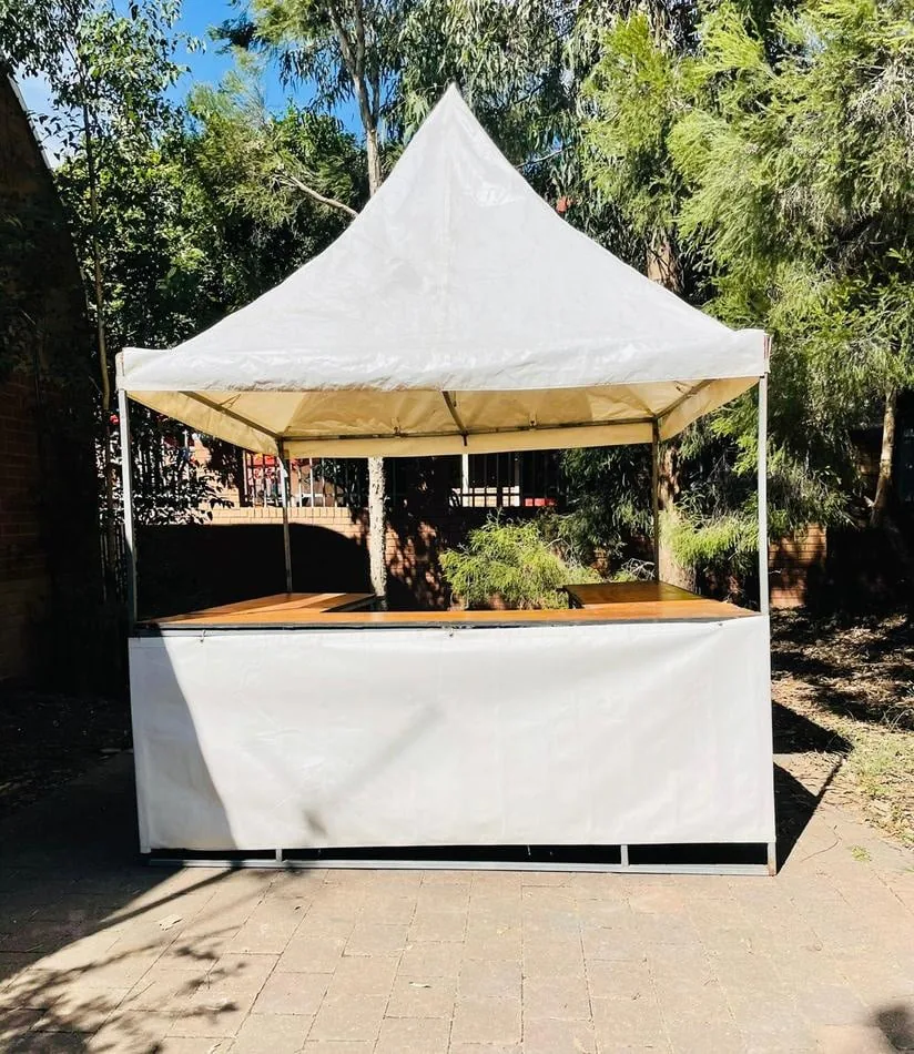 Fete Stall Hire: A white tent with a wooden table and chairs (including setup).