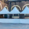 Three white tents set up in front of a brick building, available for fete stall/tent hire (including setup).