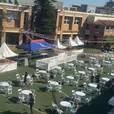 Fete stalls with cafe tables and white plastic chairs at an outdoor community event