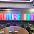Large FUTURE FIT illuminated event letters with multicoloured LED lighting at an indoor conference venue