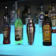 A bar with a stunning display of glowing liquor bottles on a shelf.
