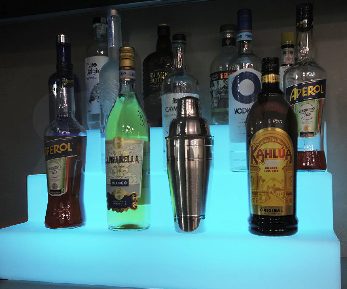 A bar with a stunning display of glowing liquor bottles on a shelf.