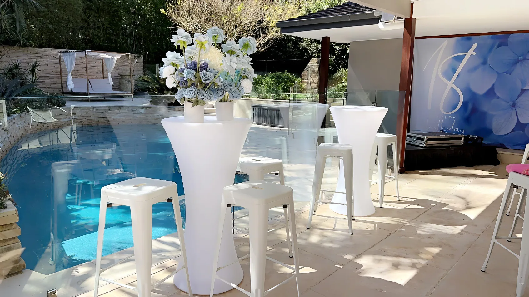 A pool party with white stools and chairs, featuring a Glow Cocktail Bar Table Hire.