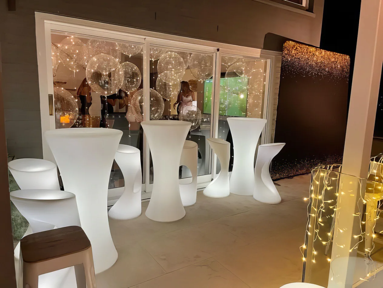 A group of white stools and a Glow Cocktail Bar Table.