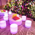 A room filled with colorful stools and plants, perfect for Glow Cylinder Seat Hire.