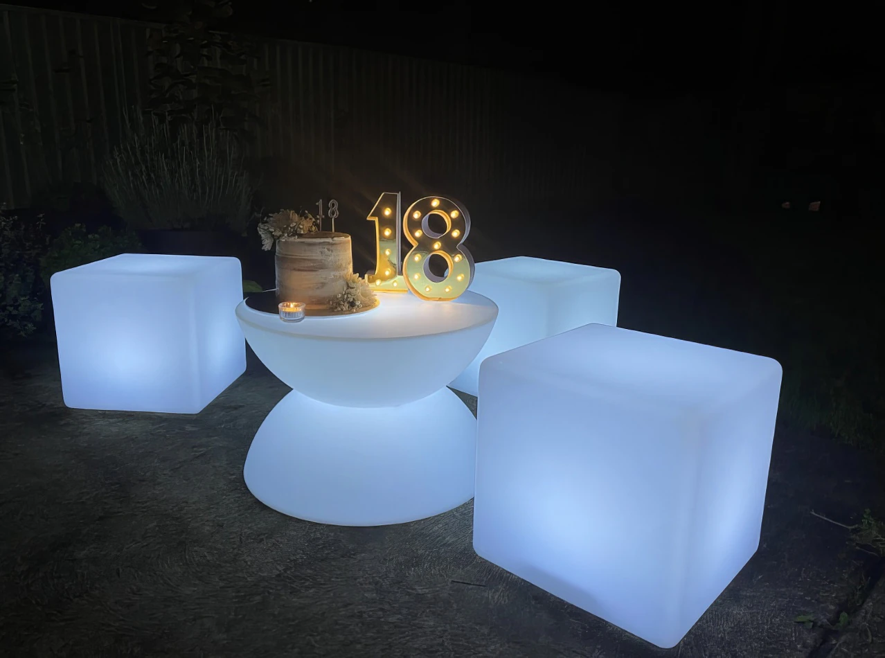 Three large white cubes sitting on a coffee table at night, emitting a gentle glow.
