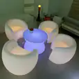 A set of white chairs and a table with LED lights illuminating the area.