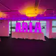 A room with purple lights and a sign that says aria, adorned with glow letters.