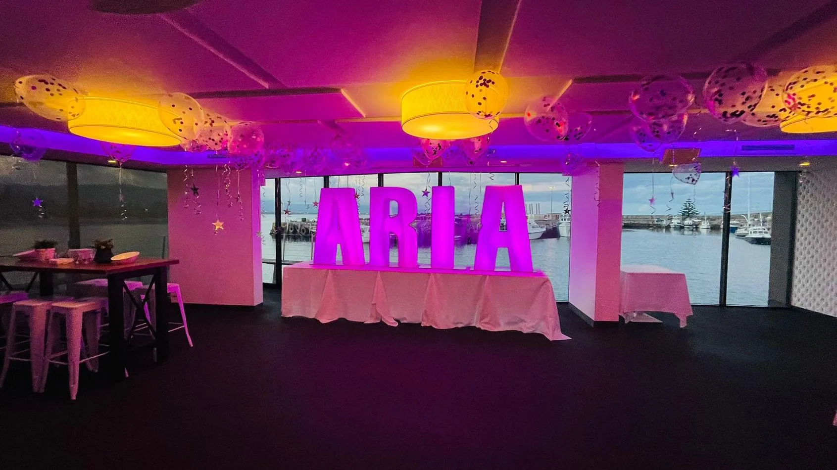 A room with purple lights and a sign that says aria, adorned with glow letters.