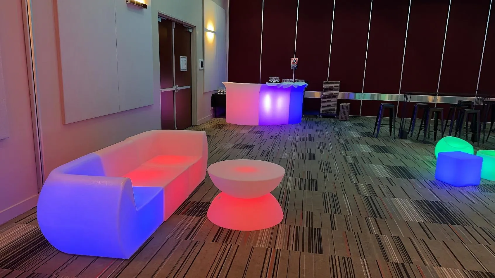         Description: A colorful Glow Lounge Suite fills the room, complementing the vibrant furniture. A table is also present, completing the lively ambiance.