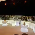A balcony bar with white glowing lights and stools for hire.