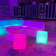 A Glow Mini coffee table and chairs with colorful lights in the middle of a room.