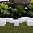 Curved glow snake benches arranged in an arc with glow rectangle benches and a glow cube on lawn at a backyard event