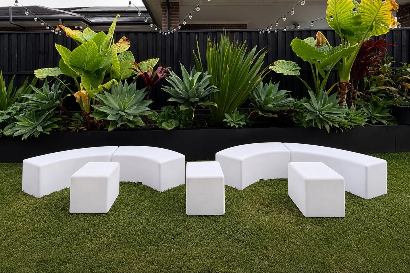 Curved glow snake benches arranged in an arc with glow rectangle benches and a glow cube on lawn at a backyard event
