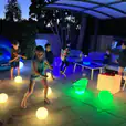 Kids playing with glowing balls in a backyard rented from Glow Sphere Hire - 20cm.