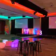 A conference room with colorful stools and a projection screen available for Glow Sphere Chair Hire.