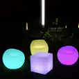 Three colorful glow sphere chairs on a grassy area.