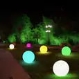A group of vibrant ball lights in a park at night, available for Glow Sphere Hire.