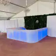 A glowing bar set up in a tent with blue lights.