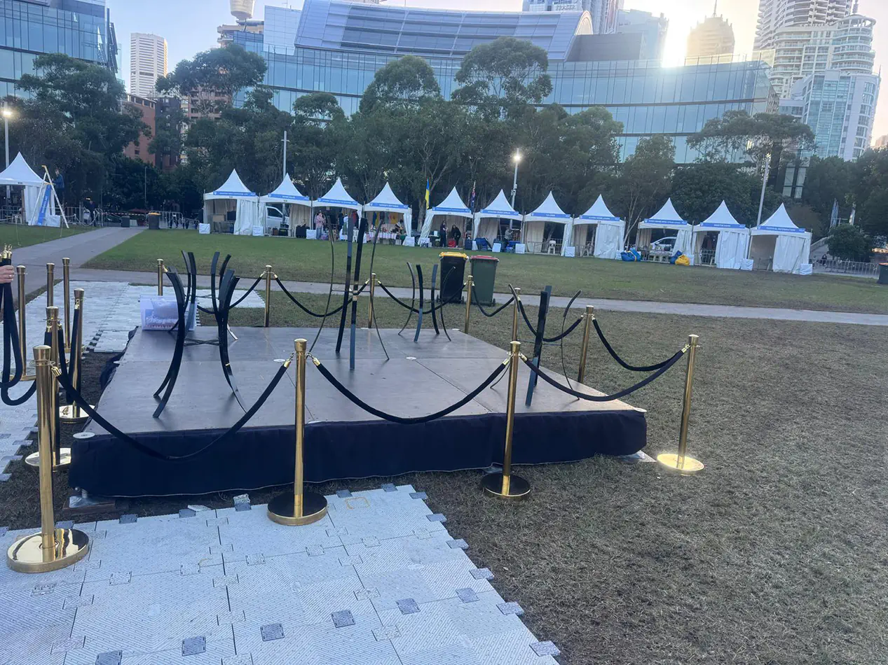 Gold bollards with black velvet ropes surrounding an outdoor event platform and entry walkway