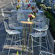 Gold hairpin leg cocktail tables paired with white wire chairs and floral centrepieces set up in an outdoor event space with modern styling
