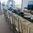 A table set up for a tea party with a view of the Sydney Harbour Bridge, featuring gold Tiffany chair hire.