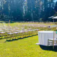 A wedding ceremony set up in a grassy field with Gold Tiffany Chair Hire.