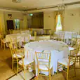 A spacious room with white tables and chairs available for Gold Tiffany Chair Hire.