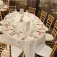 A room with tables and chairs, including Gold Tiffany Chairs, set up for a wedding.