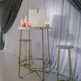 A gold table with candles and stools in front of a curtain, available for hire.