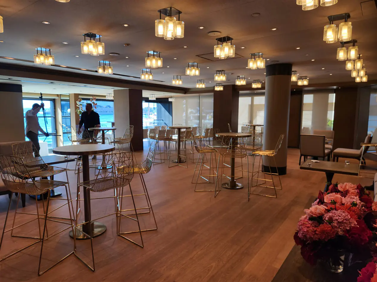 Gold wire bar stools paired with cocktail tables in a modern indoor event space with warm lighting and timber flooring