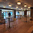 Gold wire bar stools paired with cocktail tables in a modern indoor event space with warm lighting and timber flooring