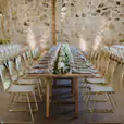 A wedding reception set up in a stone barn with gold wire chairs.