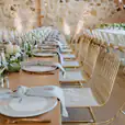 A table set up with white linens and greenery, accentuated by elegant gold wire chairs.