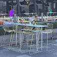 Gold wire stools arranged around a white bar table in an outdoor dining setting with floral centrepieces and glass balustrade backdrop