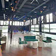 Green velvet wire lounge seating with white wire frame furniture and ottoman stools styled inside a large waterfront event venue with timber floors and harbour views