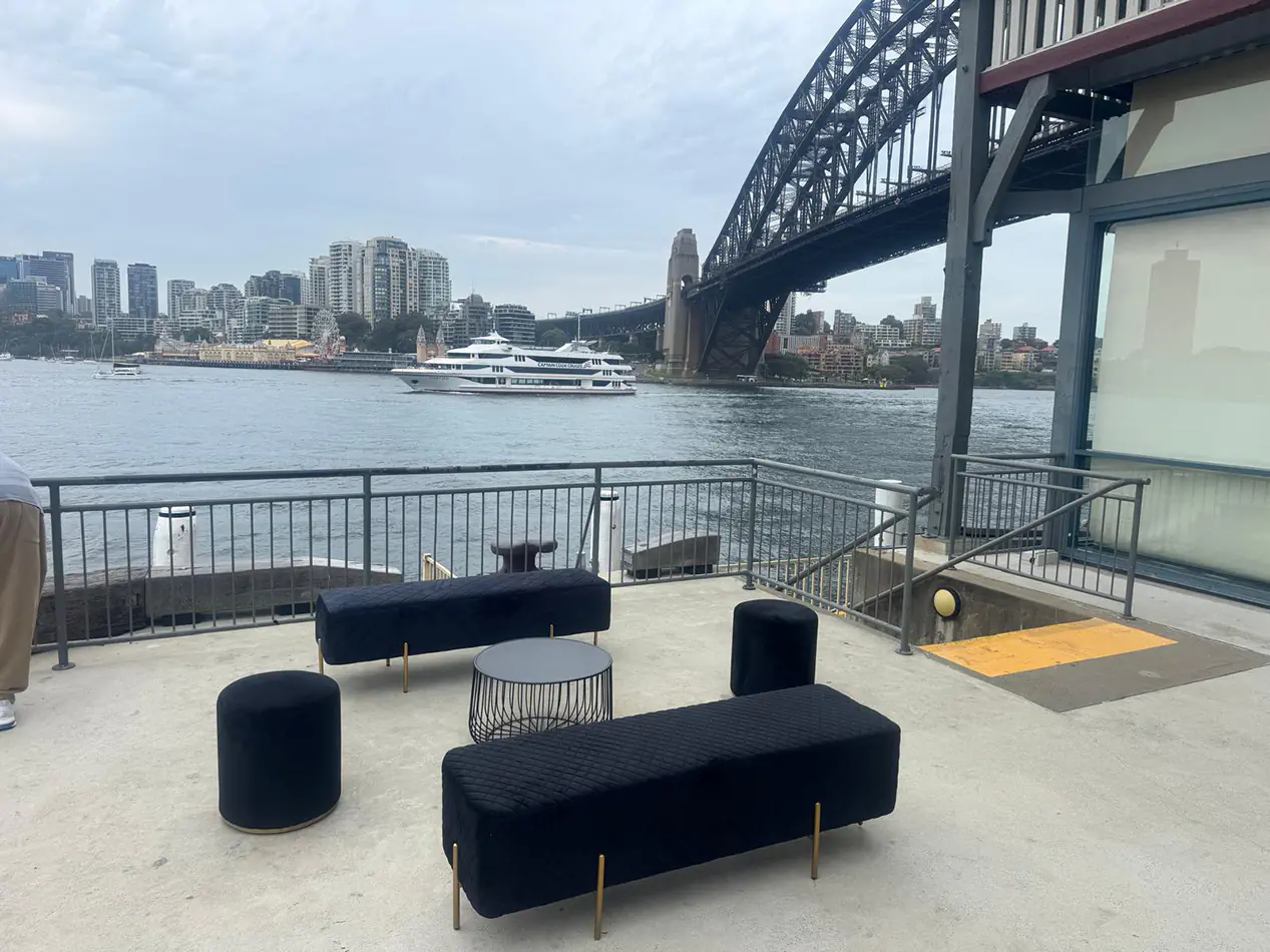 Black velvet lounge furniture and ottoman seating overlooking Sydney Harbour and the Harbour Bridge at a waterfront event venue