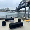 Black velvet lounge furniture and ottoman seating overlooking Sydney Harbour and the Harbour Bridge at a waterfront event venue