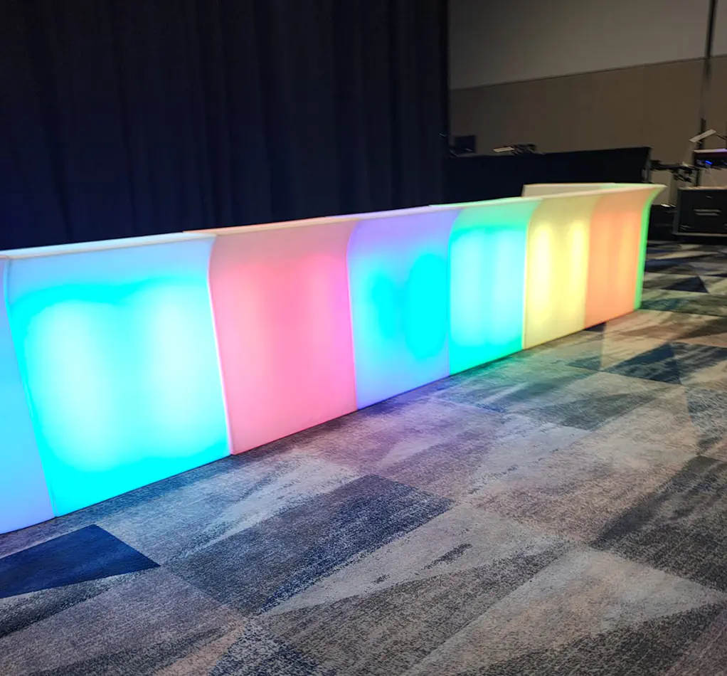 Illuminated glow bar with colour changing LED panels set up beside a stage curtain at an event venue