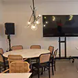 Indoor event setup with speakers, TV display and seating arrangement in a modern room with tables and chairs