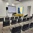 Indoor presentation setup with projection screen, PA speaker system, and audience seating arranged for a corporate event