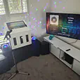 Karaoke machine setup with speakers, microphones and screen displaying music interface in a home environment with coloured party lights