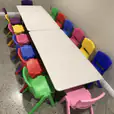 A room full of colorful plastic chairs and tables available for Kids Table Hire.